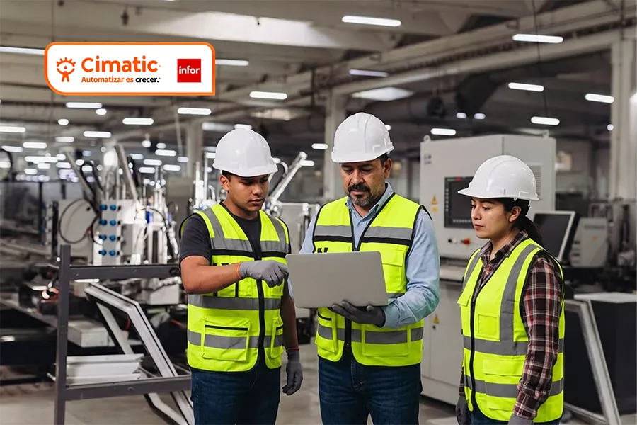 ERP para Manufactura. Equipo de supervisores y operarios con casco y chaleco de seguridad revisando información en una laptop dentro de una planta de manufactura industrial.
