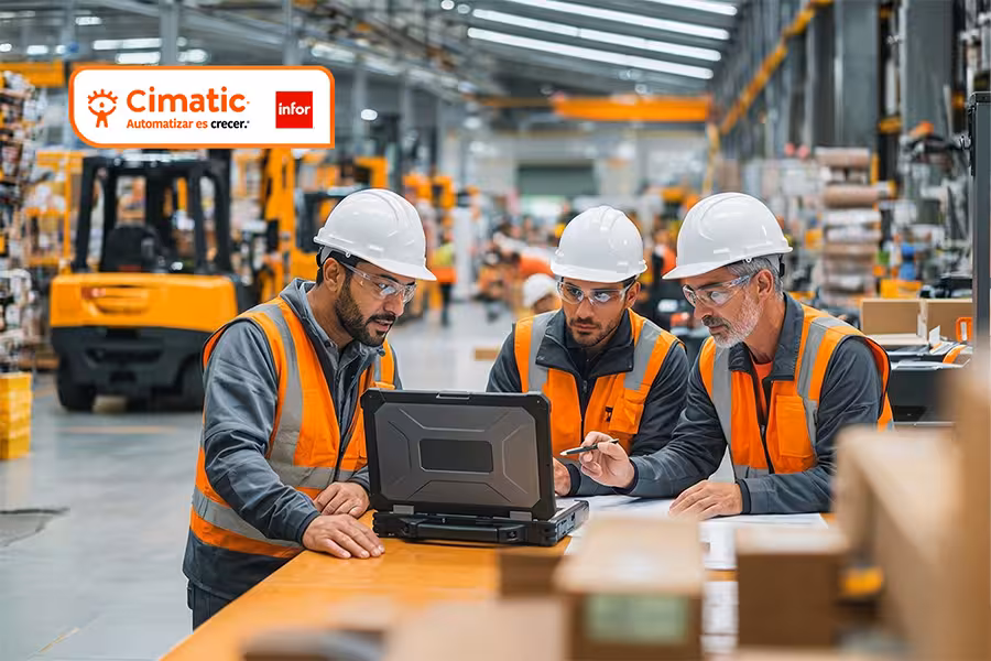 Sistema Infor ERP Cimatic. Tres hombres con cascos de seguridad blancos y chalecos de alta visibilidad naranjas, dos jóvenes y uno mayor, están de pie alrededor de una mesa de madera.